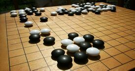 Традиционная доска для го (гобан) деревянная, с нарисованными линиями. Камни имеют двояковыпуклую форму; соседние камни почти касаются друг друга