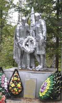 Воины, мужчина и женщина со знаменем, преклонившись, возлагают венок. Братская могила военнослужащих Красной Армии, погибших в годы Великой Отечественной войны (1942—1943)
