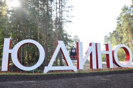 Въездной знак в посёлок Юдино. Рядом с ним установлен символ Юдина памятник-паровоз «Л-1591»