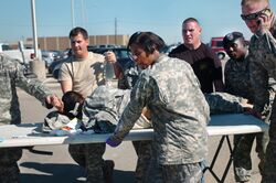 Раненого американского солдата несут к машине скорой помощи, используя стол в качестве носилок