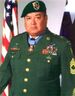 Head and shoulders of a middle-aged Hispanic man wearing a beret with unit patch and green military jacket with five rows of medals hanging from ribbons pinned to his chest and another medal hanging from his neck.