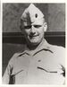 Head and shoulders of a smiling white man wearing a light-colored garrison cap and buttoned-down shirt with a bar-shaped pin on each side of the collar.