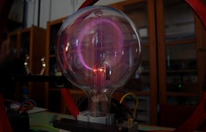 A round glass vacuum tube with a glowing circular beam inside