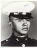 Head of a young Hispanic man wearing a white peaked cap with black visor and a dark military jacket with an eagle-globe-and-anchor pin on either side of the upright collar.