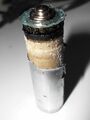 Цинковый стаканчик («-» электрод) частично вскрыт, под ней бумажный стаканчик, пропитанный электролитом и залитый битумной мастикой