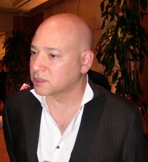 A bald man wearing a white shirt and a black jacket.