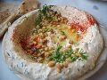 Тарелка хумуса, украшенная паприкой, оливковым маслом и кедровыми орешками.