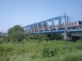 Электричка серии Е233 пересекает реку Тама между станциями Кумагава и Хигаси-Акиру