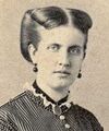 Photographic portrait of a young lady with light-colored hair swept back and wearing a high-necked, Victorian era striped dress, dark earrings and a dark locket suspended around her neck on a ribbon