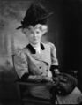 Джейн ван Миддлсворт Беллис Суза, жена Джона Филипа Суза, «короля маршей», фото около 1905 г. На ней надет клетчатый костюм с рукавами до локтя и длинными перчатками, в руках она держит ридикюль-муфту.