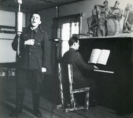 Концерт во время Войны-продолжения: Олави Вирта поёт, другой солдат играет на пианино