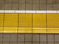 Тактильные покрытия установлены на платформе японской железнодорожной станции. Линейные направляющие блоки с выступающей одной полосой, в нижней части изображения указывают на границу безопасной «внутренней» стороны платформы противоположной от стороны где расположены рельсовые пути.