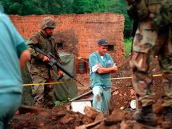 Морские пехотинцы США обеспечивают безопасность сотрудников Королевской канадской конной полиции во время исследования захоронения в косовской деревне 1 июля 1999 года.