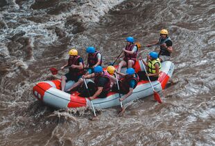 Сплав по горной реке на большом 6 местном лодке с инструктором, в середине лодки сидят дети. Оценивая по фото уровень сложности 3