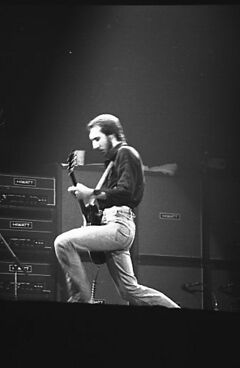 An older man playing a red guitar