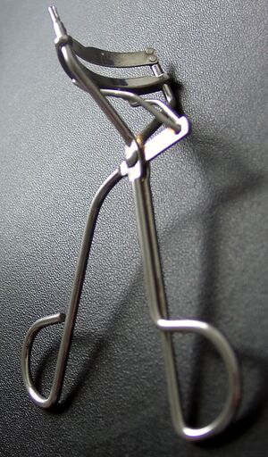 The picture shows a metal eyelash curler laying on its side